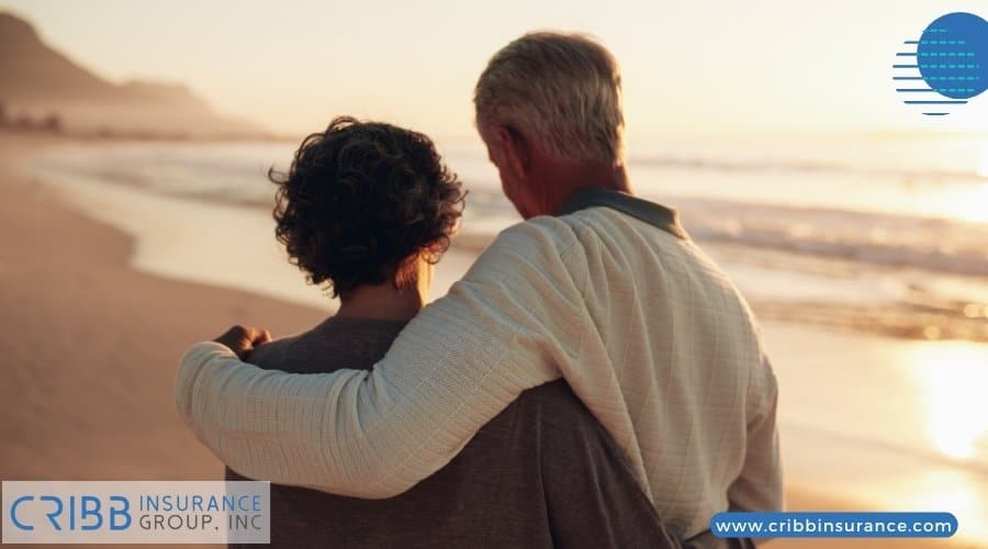 An elderly couple walking on a beach during sunset