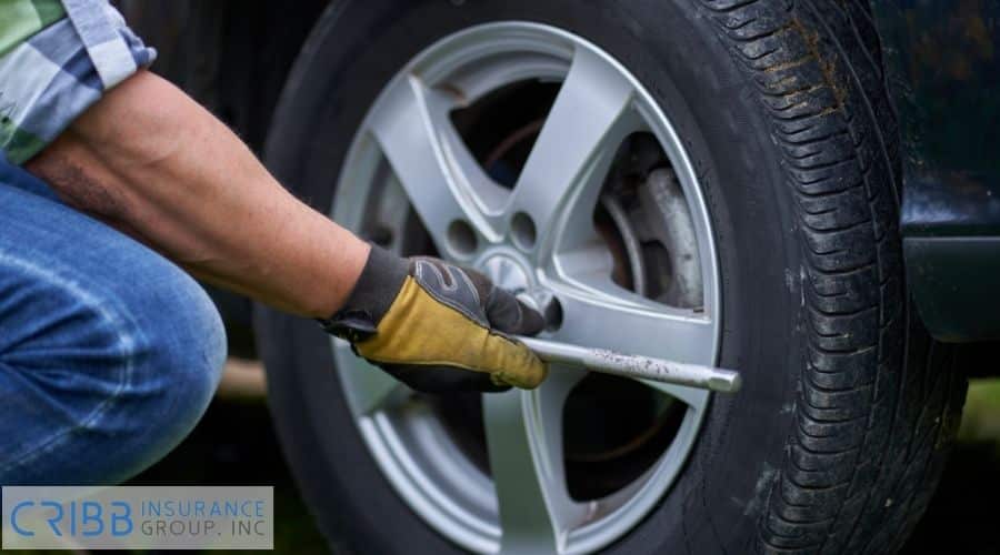 Roadside assistance changing a flat tire for a driver.